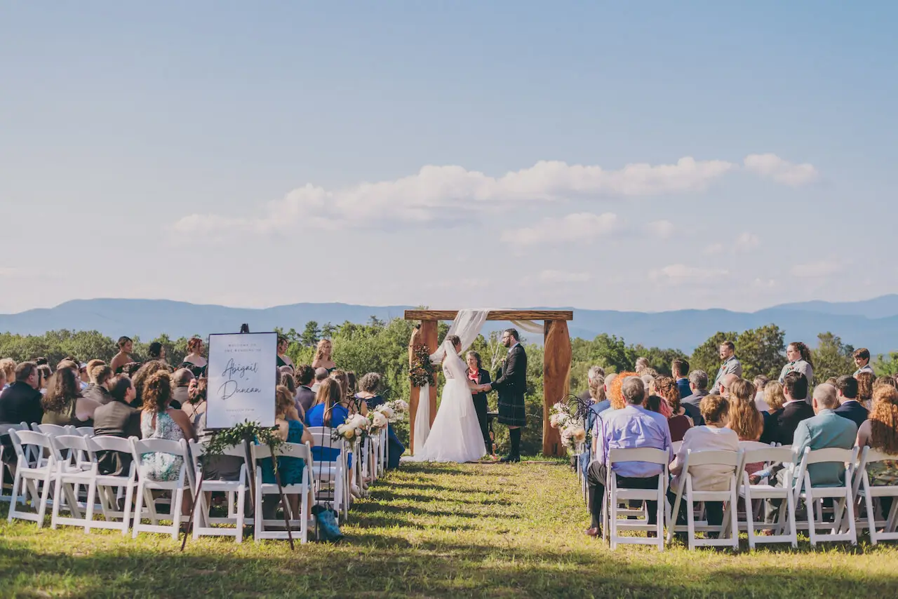 An outdoor wedding ceremony with guests and mountain views